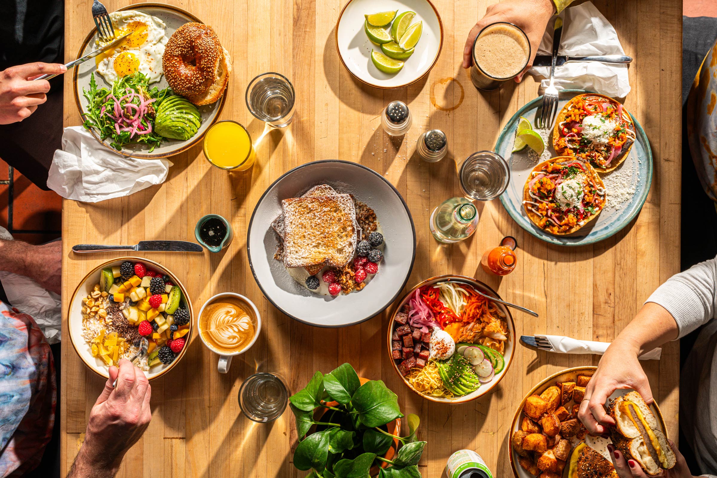 Top view of a table full of diverse breakfast dishes and coffee and juice glasses shared by several people on wooden table